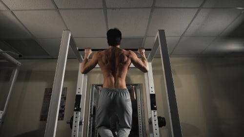 Rückansicht Porträt eines muskulösen Mannes, der sich im Studio des Fitnessstudios strafft