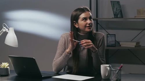 Woman Writing at a Desk With Laptop