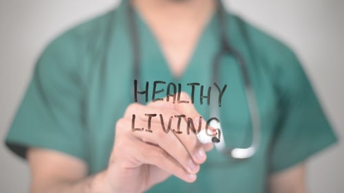 Medical Professional Writing Healthy Living on Clear Screen