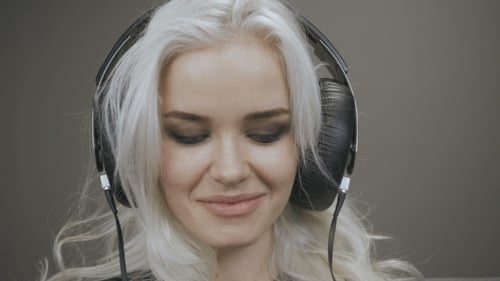 Young Woman Smiles Wearing Big Black Headphones