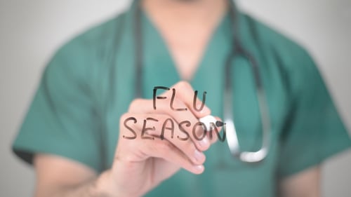 Medical Professional Writing Flu Season on Screen