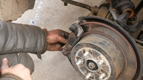 Auto Mechanic Working On Brakes In Car Repair Shop