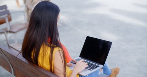 Woman working on laptop sitting on bench