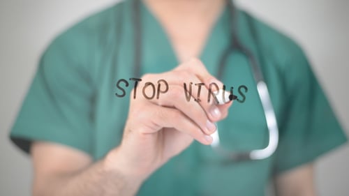 Medical Professional Writes "STOP VIRUS" on Transparent Surface