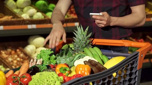 Man Shopping Groceries with Phone in Supermarket