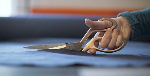 Woman Cutting Fabric with Gold Handled Scissors