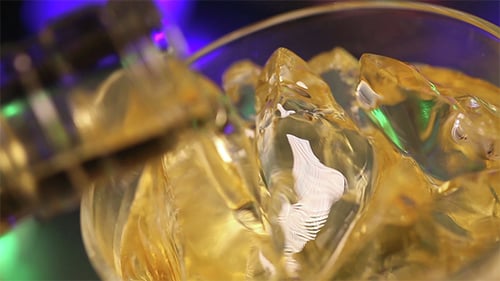 Whiskey Poured into Glass with Ice Cubes
