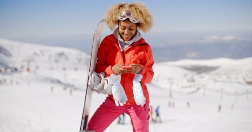 Woman Snowboarding with Smartphone in Snowy Mountains