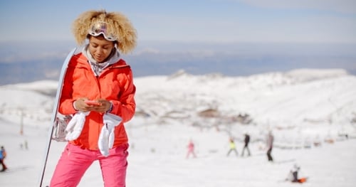 Woman with Snowboard Using Phone on Snowy Mountain