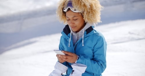 Woman Using Phone on Snowy Winter Mountain