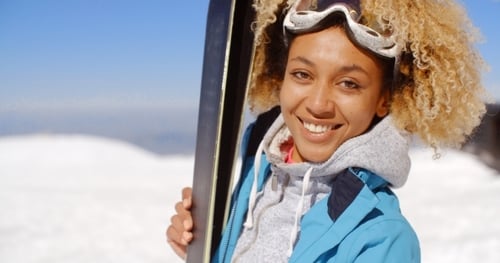 Attractive Woman Smiling Holding Skis in Snowy Mountain