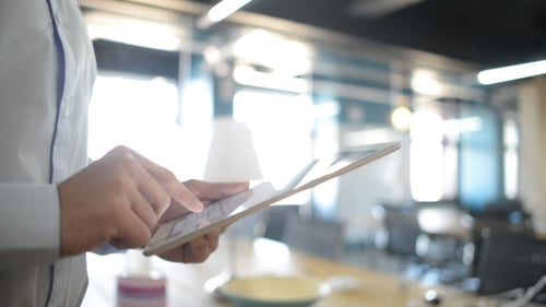 Young Adult Uses Tablet in Bright Office Setting