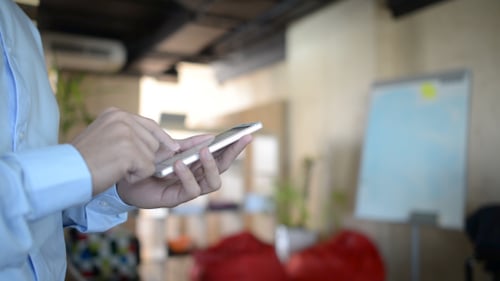 Young Adult Using Cell Phone in Modern Office