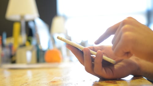 Fingers Scrolling on Smartphone on Wooden Table