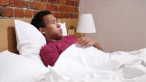 Un homme africain malade allongé dans son lit la nuit se sent mal à l'aise