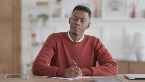 African Man Having Failure while Writing on Paper in Office