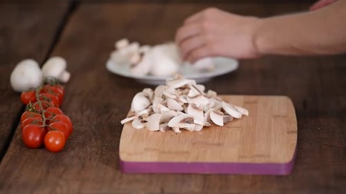 Slicing Fresh Mushrooms Next to Cherry Tomatoes