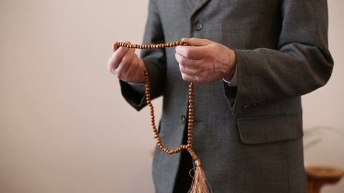 Betende Hände mit Rosenkranzperlen eines alten Mannes