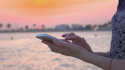 Woman Using Phone at Sunset on Tropical Beach