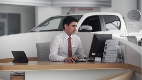 Car Salesman Sitting In Showroom