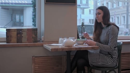 Woman In Cafe Pouring Tea From The Teapot Into a White Ceramic Cup