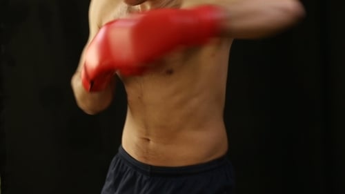 Muscular Man Boxing with Red Gloves on Black