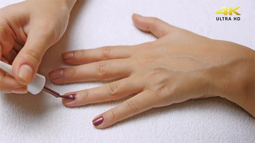 Woman Applies Dark Red Nail Polish to Fingers