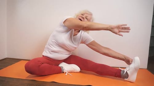 Senior Woman Stretching on Yoga Mat Indoors