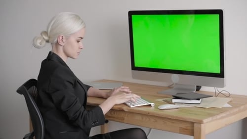 Young Woman Using Computer With Green Screen Display