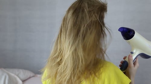 Young Adult Drying Blonde Hair with Hair Dryer