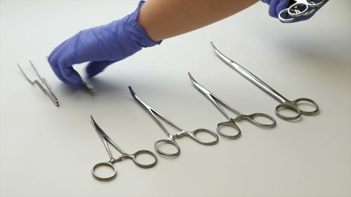 Gloved Hand Organizing Shiny Surgical Instruments