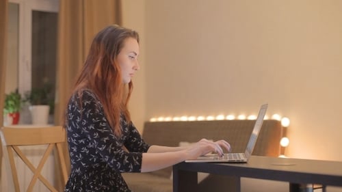 Woman Working on Laptop at Desk in Home