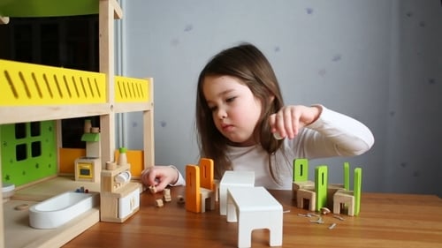 Girl Playing with a Wooden Dollhouse at Home