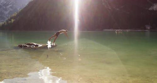 Junger aktiver Mann läuft und taucht in den wilden sonnigen klaren See