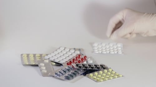 Gloved Hand Organizing Colorful Packaged Pills