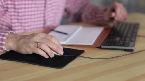 Mann arbeitet mit einer Computermaus am Tisch