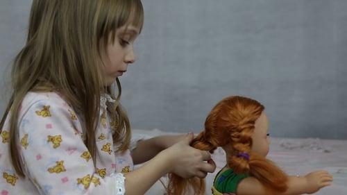 Girl Braiding Doll's Hair at Home