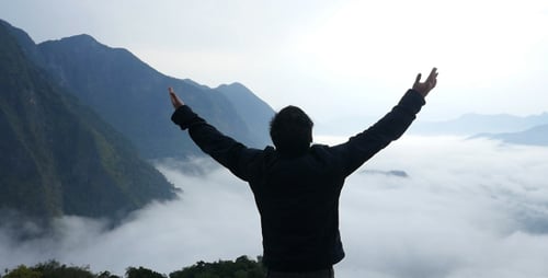 Man Surveys Tropical Mountain Landscape Above the Clouds