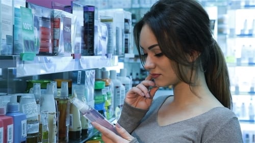 женщина изучает этикетку шампуня в магазине