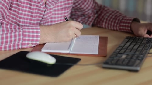 Mann sitzt am Computer und schreibt in das Tagebuch
