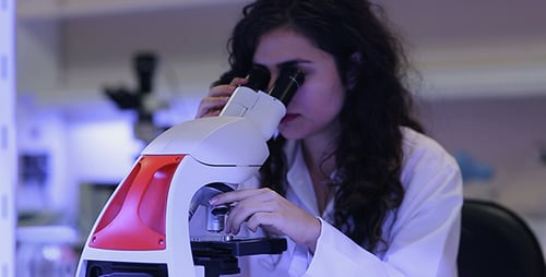 Young Adult Woman Using Microscope in Lab