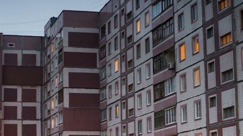 Mehrstöckiges Gebäude mit wechselnder Fensterbeleuchtung bei Nacht.