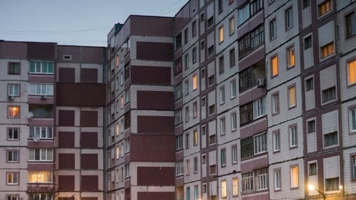 Mehrstöckiges Gebäude mit wechselnder Fensterbeleuchtung bei Nacht.