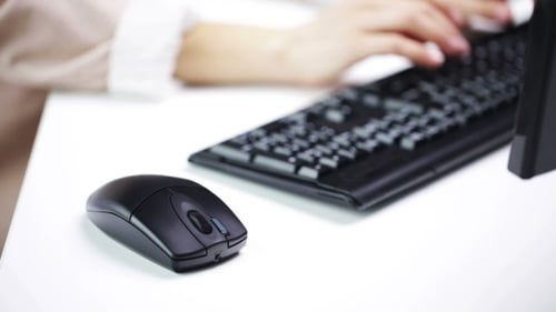 Frau tippt auf Computertastatur im Büro