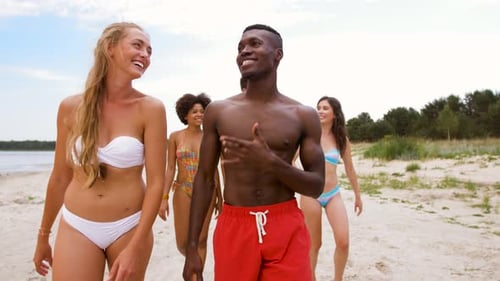 Mixed Race Couple Walking Along Beach with Friends