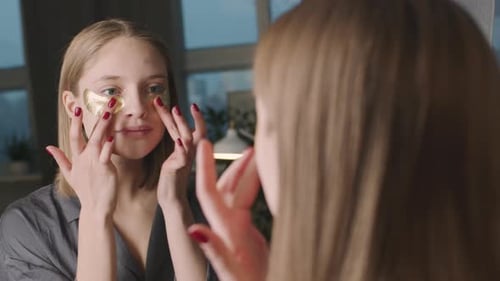 Woman Applying Eye Patches in the Mirror