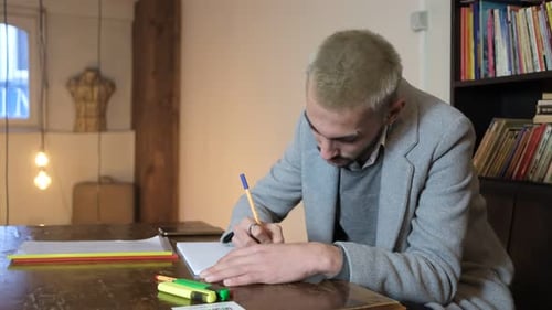 Young Adult Writing in Notepad at Table
