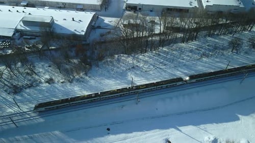 Flight over the railroad. A train runs along the rails. Winter industrial landscape.