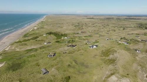 Eine Luftaufnahme Kleine Häuser stehen zwischen hohen und grasbewachsenen Sanddünen.