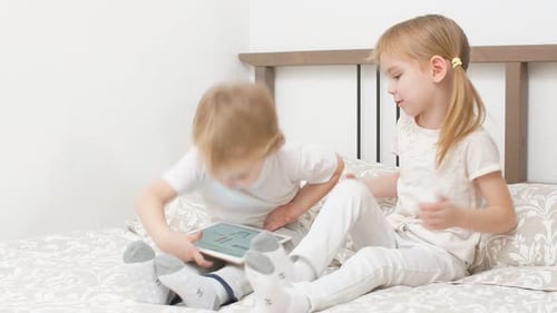 Blond Children Play with Tablet on Bed